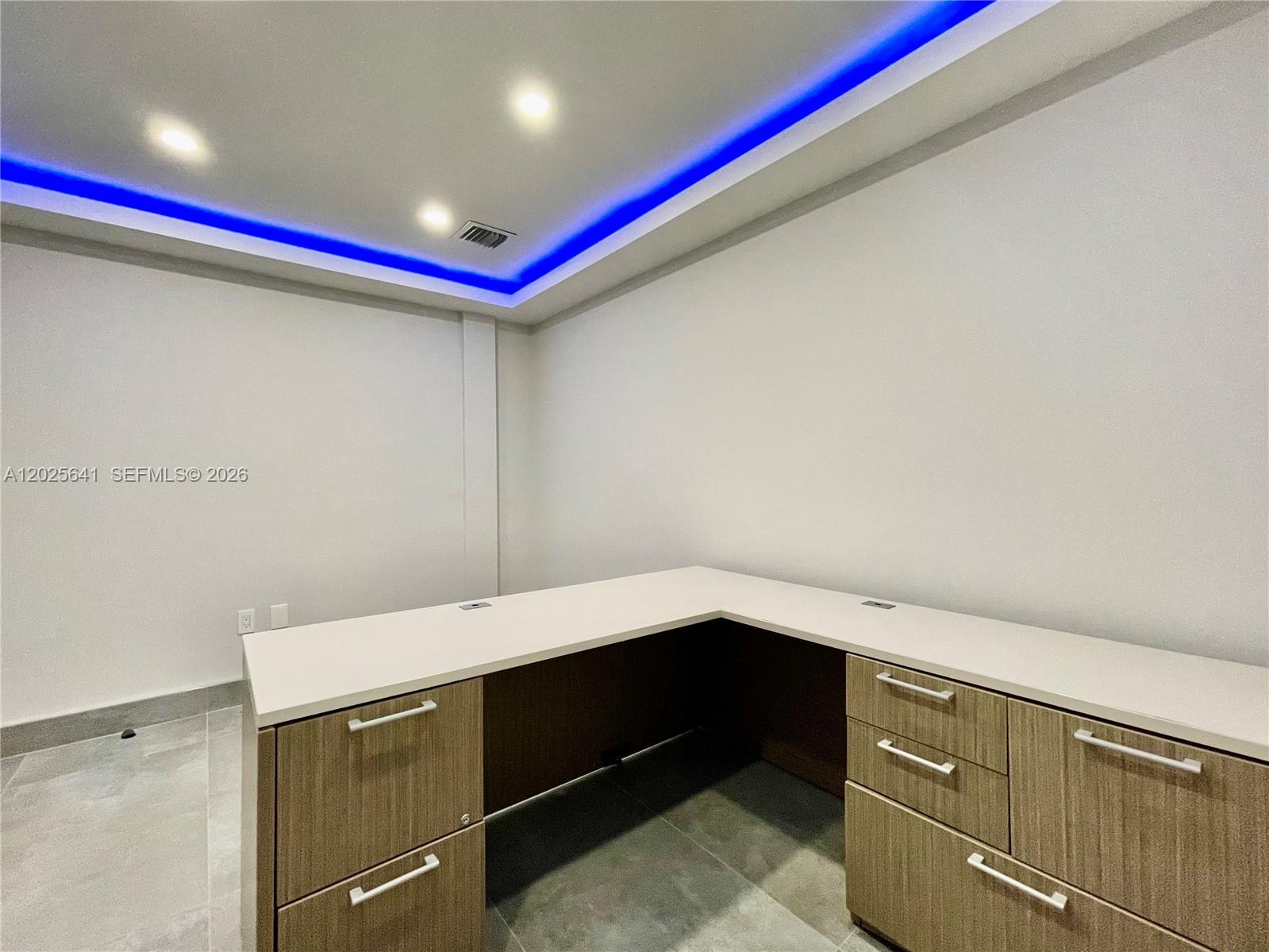 An office space features an L-shaped desk with wood cabinetry and blue tray ceiling lighting — 6280 W Atlantic Blvd, Margate FL 33063, MARGATE, FL
