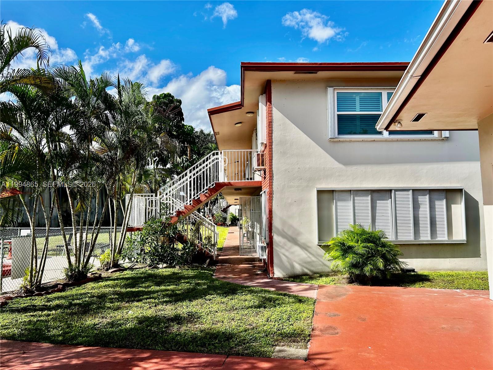 An exterior view of a two-story apartment building with stairs and a palm tree — 2918 Funston St # 29B, Hollywood FL 33020, HOLLYWOOD, FL