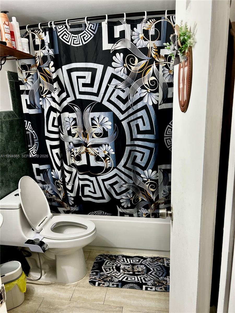 A bathroom features a toilet with a bidet attachment and a patterned shower curtain — 2918 Funston St # 29B, Hollywood FL 33020, HOLLYWOOD, FL
