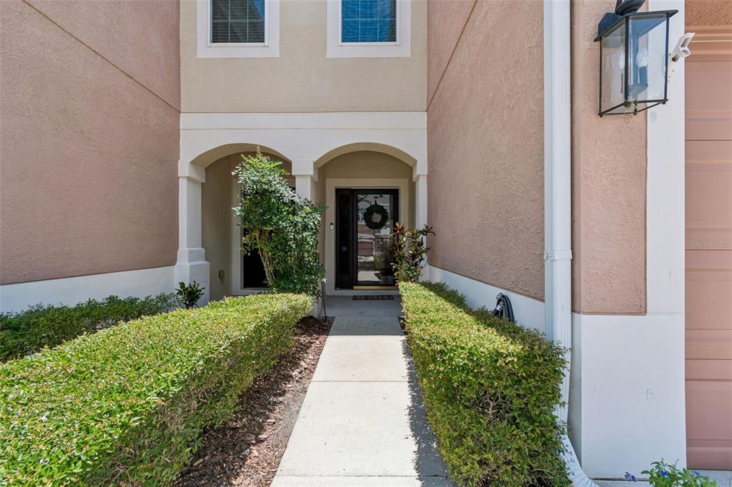 A concrete walkway leads to the front entrance of a two-story stucco home — 26606 CASTLEVIEW WAY, WESLEY CHAPEL, FL
