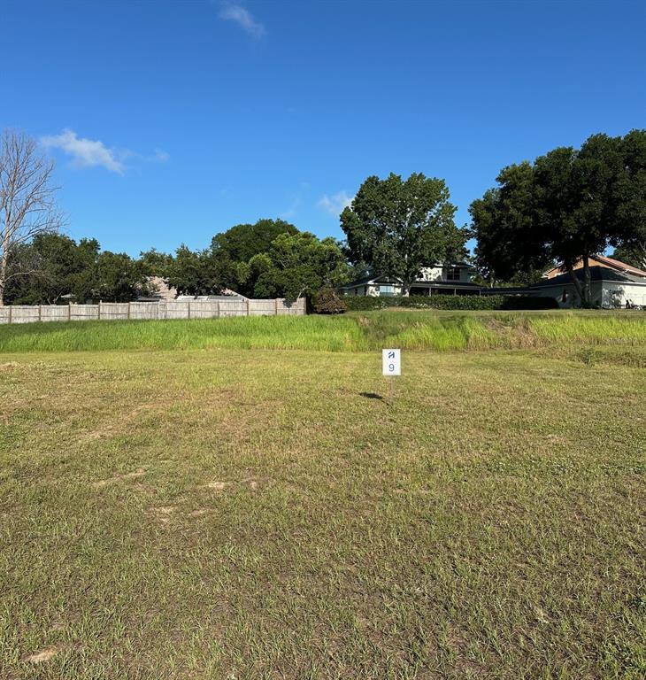 A vacant, grassy lot features a small sign labeled with the number nine — 11627 MATANILLA DRIVE, CLERMONT, FL
