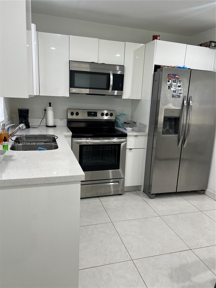 A kitchen features white cabinets, stainless steel appliances, and light-colored countertops — 2954 NW 57th St # 2954, Miami FL 33142, MIAMI, FL