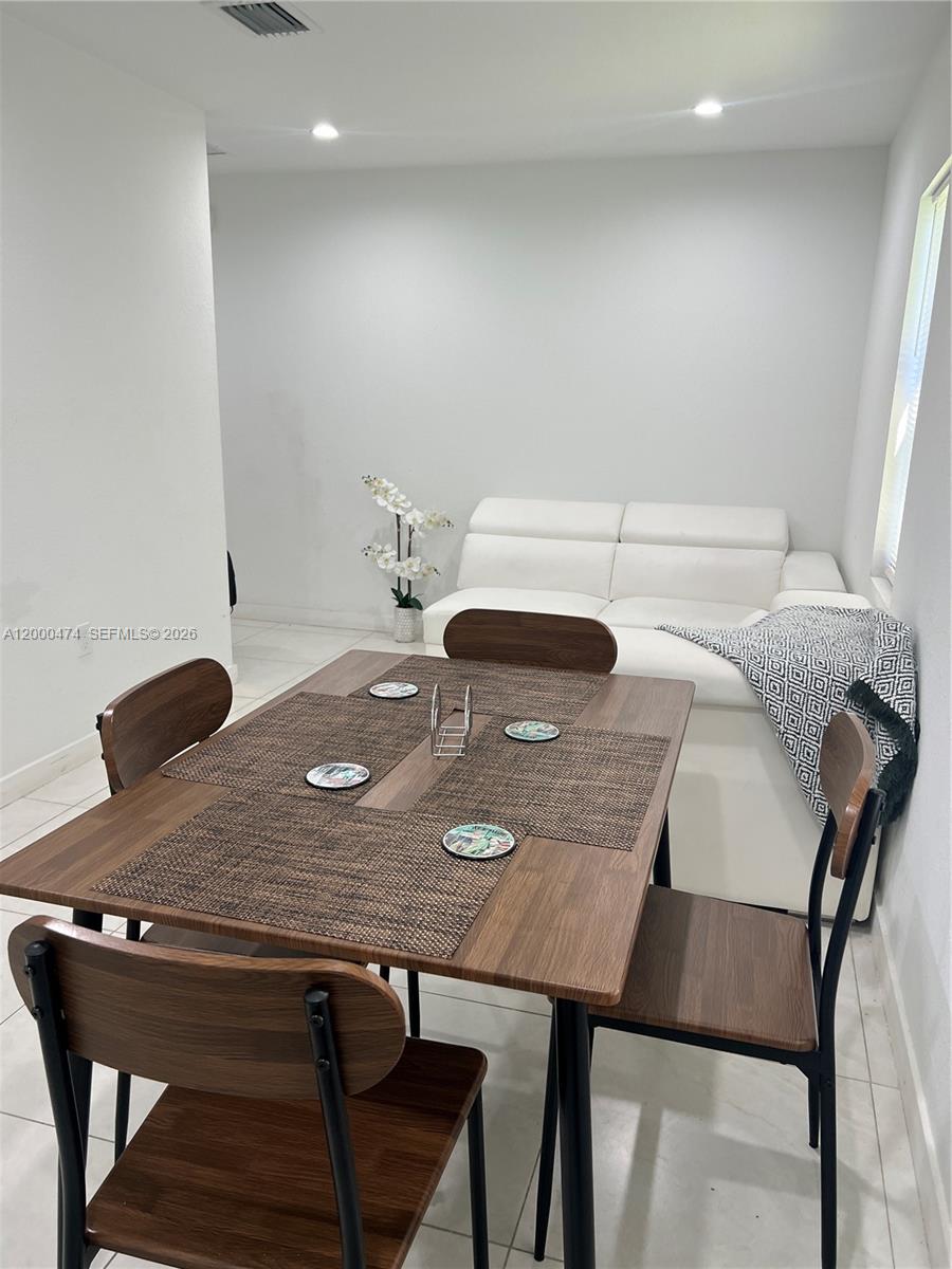 A dining area features a wooden table with four chairs positioned in front of a sofa — 2954 NW 57th St # 2954, Miami FL 33142, MIAMI, FL