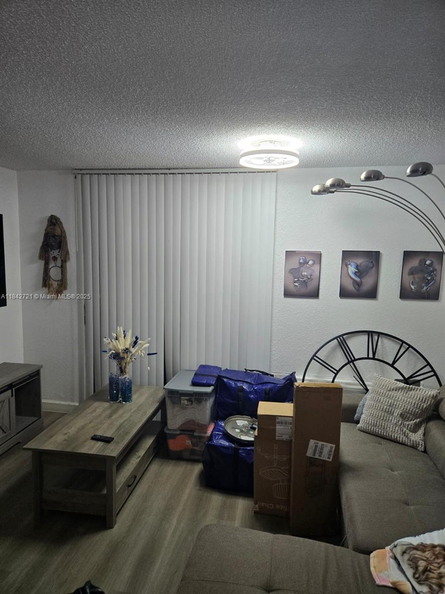 A living room features a gray sofa, a wood coffee table, and stacked storage bins — 16450 NW 2nd Ave # 310, Miami FL 33169, MIAMI, FL