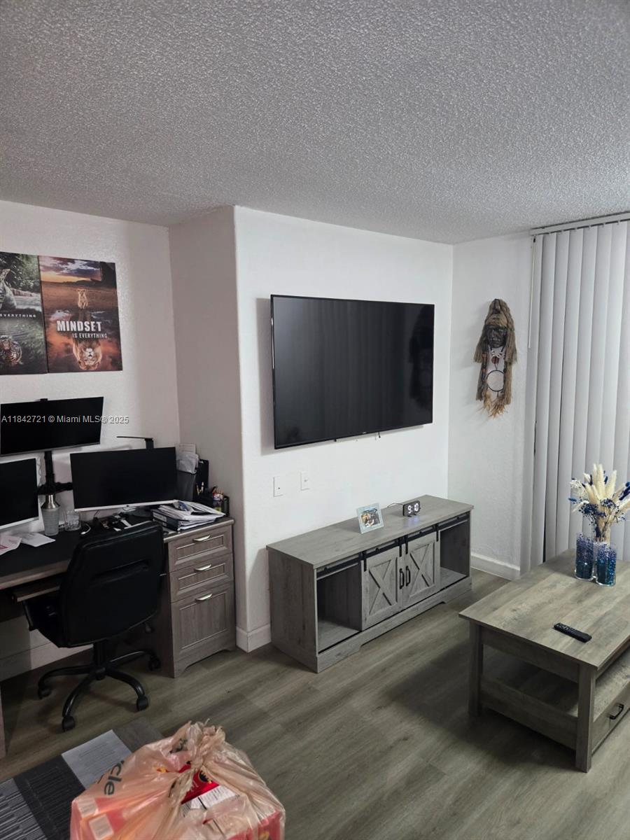 A living room features a wall-mounted television, a grey media console, and a desk area — 16450 NW 2nd Ave # 310, Miami FL 33169, MIAMI, FL