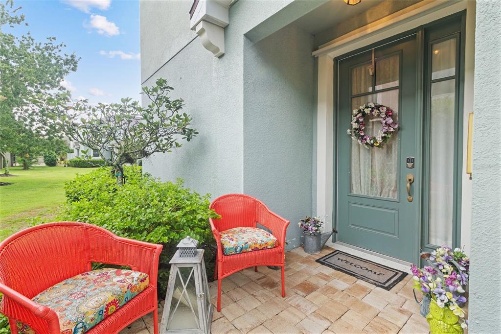 A front porch features two red wicker chairs, a lantern, and a green door — 12356 TRAILHEAD DRIVE, BRADENTON, FL