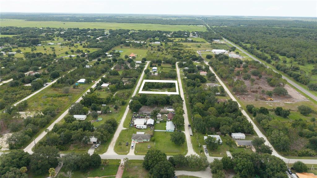 An aerial view shows a rectangular vacant lot outlined in white within a rural neighborhood — NE 2ND TERRACE, OKEECHOBEE, FL
