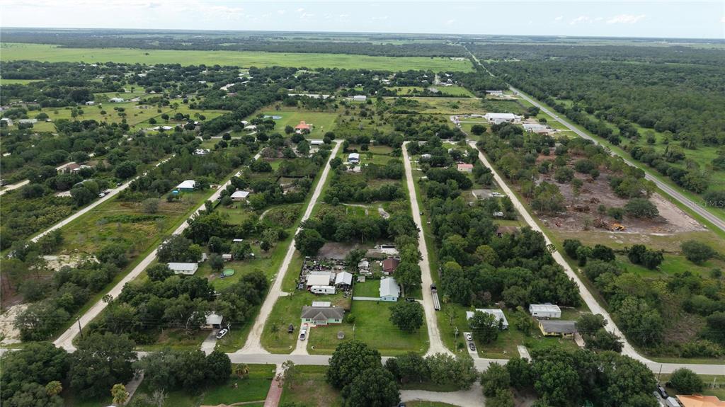 An aerial view shows a rural residential neighborhood with scattered houses, trees, and dirt roads — NE 2ND TERRACE, OKEECHOBEE, FL