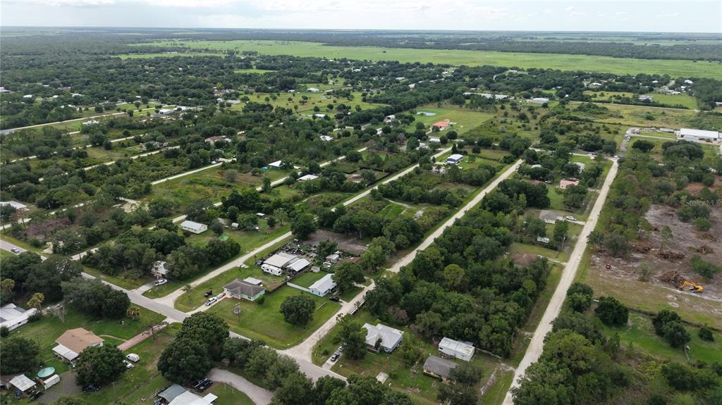 An aerial view shows a rural residential neighborhood with scattered houses, trees, and dirt roads — NE 2ND TERRACE, OKEECHOBEE, FL