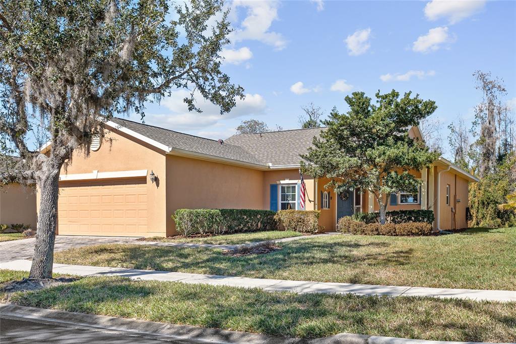 A single-story tan house with a two-car garage and a front yard with trees — 632 PORTOFINO DRIVE, KISSIMMEE, FL