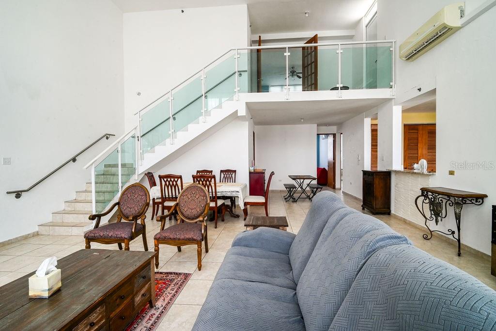 A living room with a staircase, glass railing, tiled floors, and a lofted upper level — 9 PALACIOS DEL ESCORIAL UNIT 9-71, CAROLINA, PR