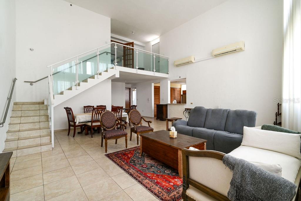 A living room with a staircase, glass railing, dining area, and high ceilings — 9 PALACIOS DEL ESCORIAL UNIT 9-71, CAROLINA, PR