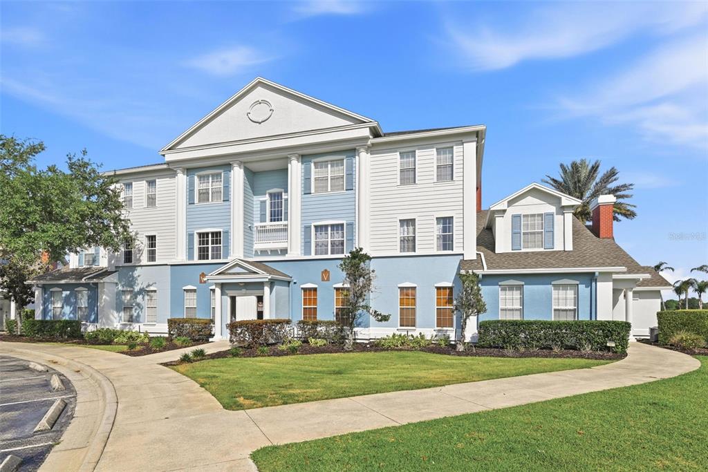 A three-story building with blue and white siding features a central portico and columns — 7603 HERITAGE CROSSING WAY UNIT 102, REUNION, FL