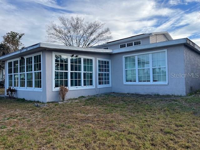 A light-colored, single-story house with a large sunroom featuring many windows — 635 LAKE HOLLOWAY BOULEVARD, LAKELAND, FL