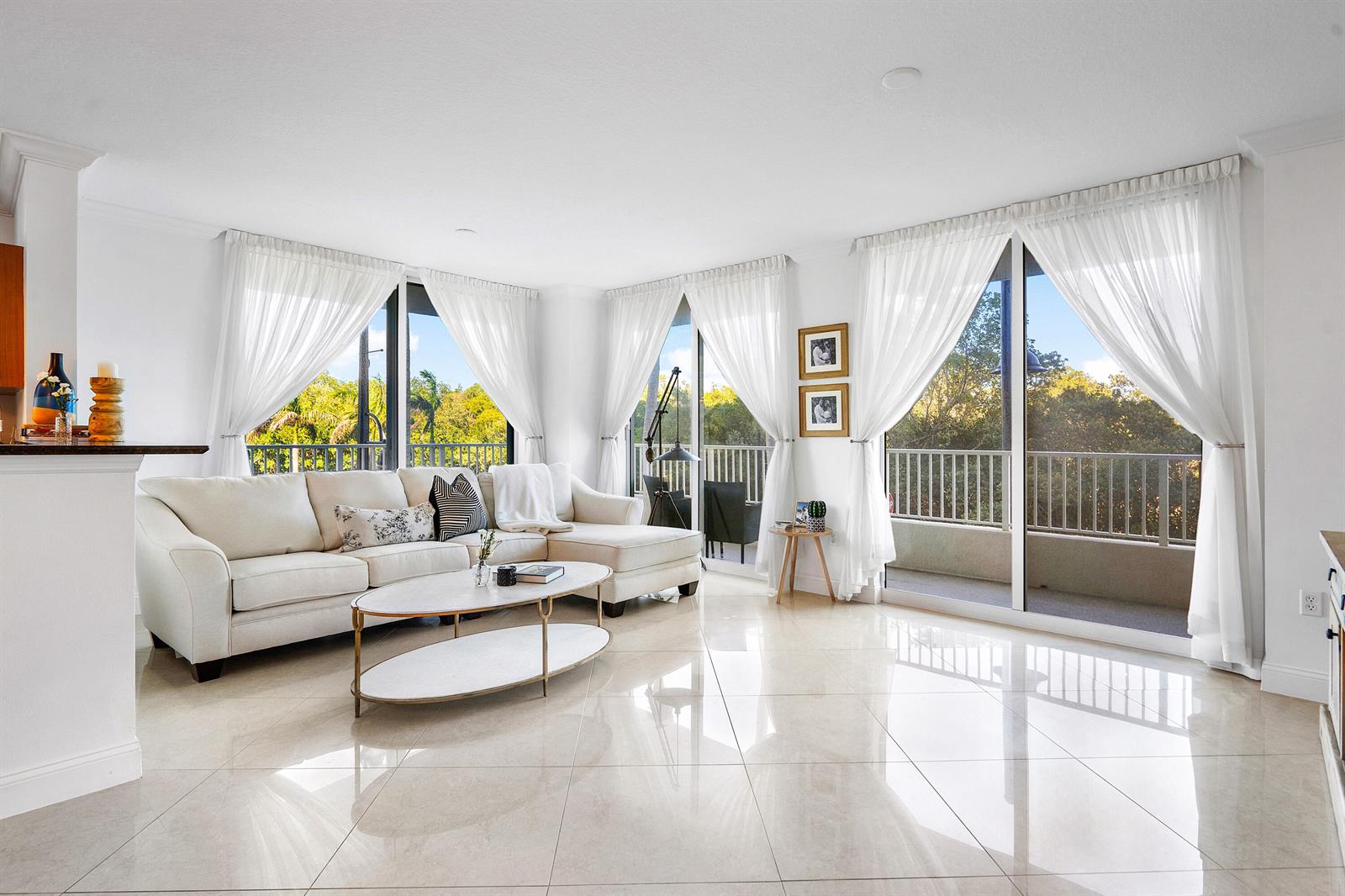 A bright living room features a white sectional sofa, marble coffee table, and large sliding doors — 700 E Boynton Beach Boulevard # 202, Boynton Beach FL 33435, BOYNTON BEACH, FL