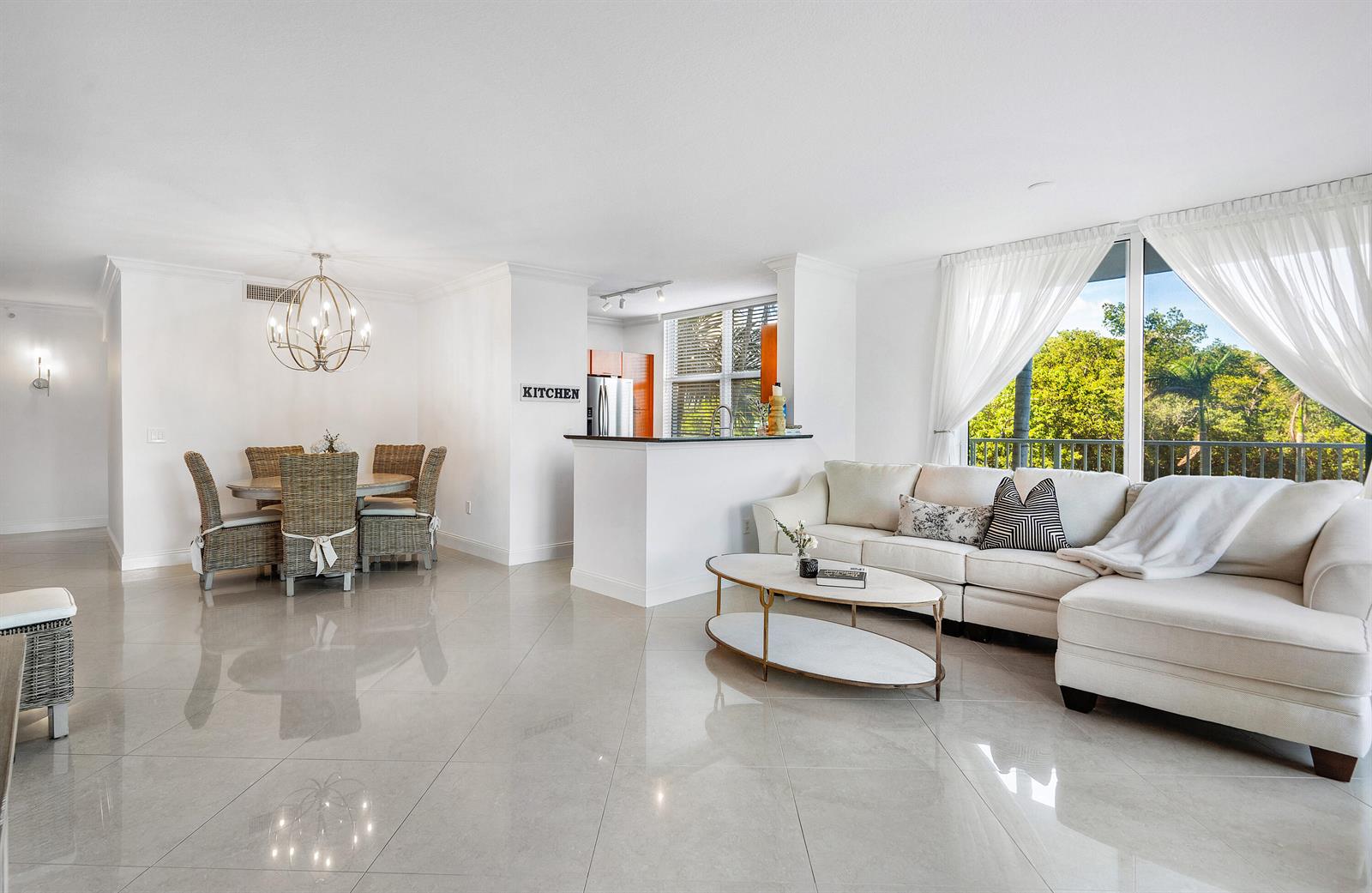 An open-concept living and dining area features white tile floors, a sectional sofa, and balcony views — 700 E Boynton Beach Boulevard # 202, Boynton Beach FL 33435, BOYNTON BEACH, FL