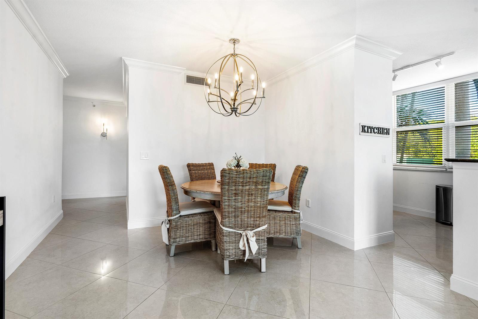 A dining area features a round wooden table, four wicker chairs, and a spherical chandelier — 700 E Boynton Beach Boulevard # 202, Boynton Beach FL 33435, BOYNTON BEACH, FL