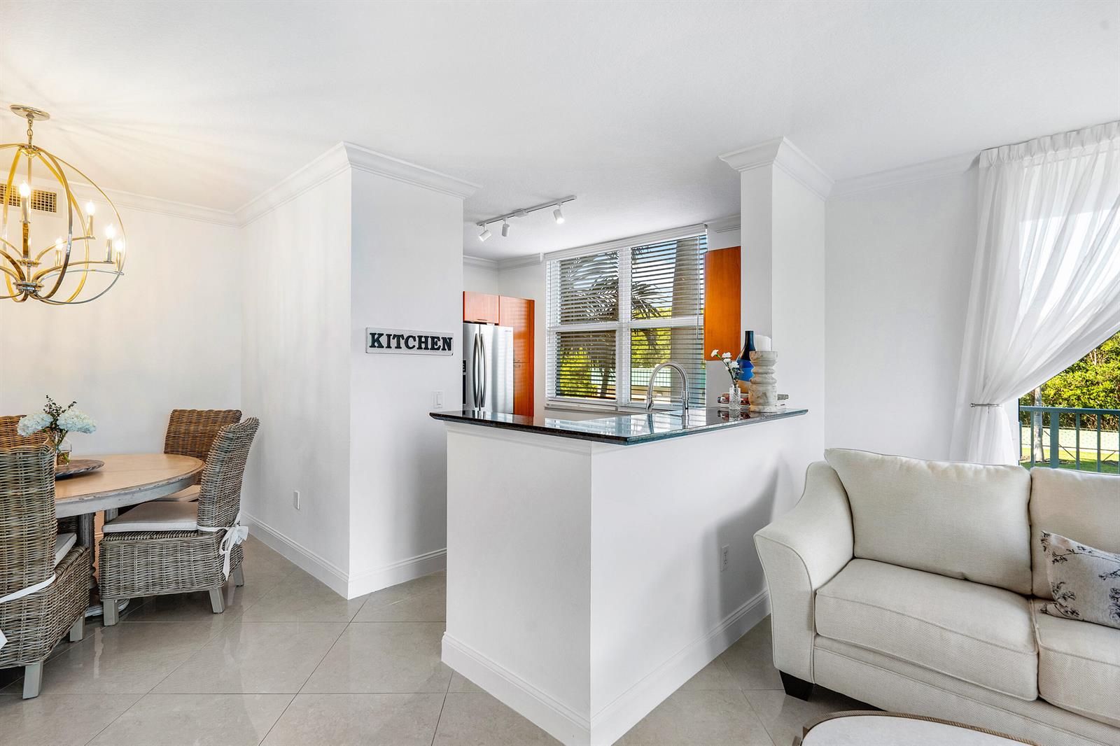 A kitchen with a breakfast bar opens into a dining area and living room — 700 E Boynton Beach Boulevard # 202, Boynton Beach FL 33435, BOYNTON BEACH, FL