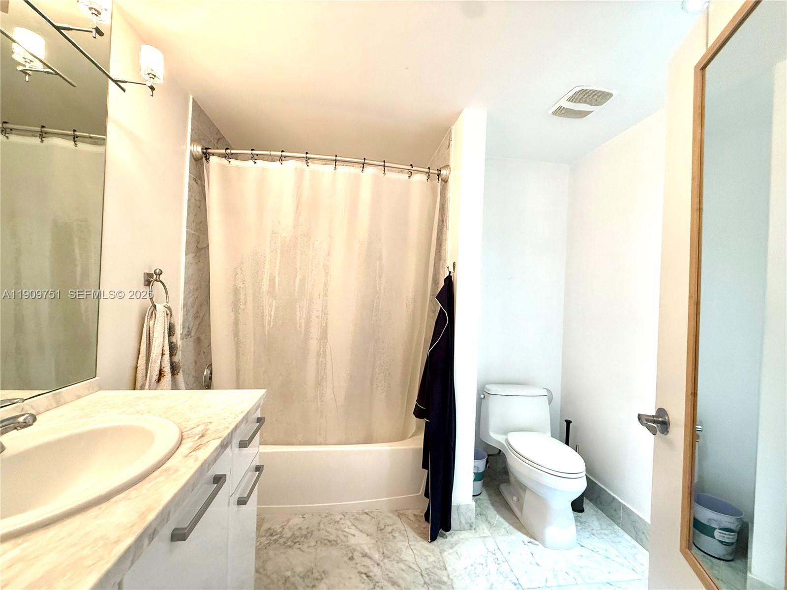 A bathroom features a marble-topped vanity, a shower-tub combination, and a white toilet — 253 NE 2nd St # 219, Miami FL 33132, MIAMI, FL