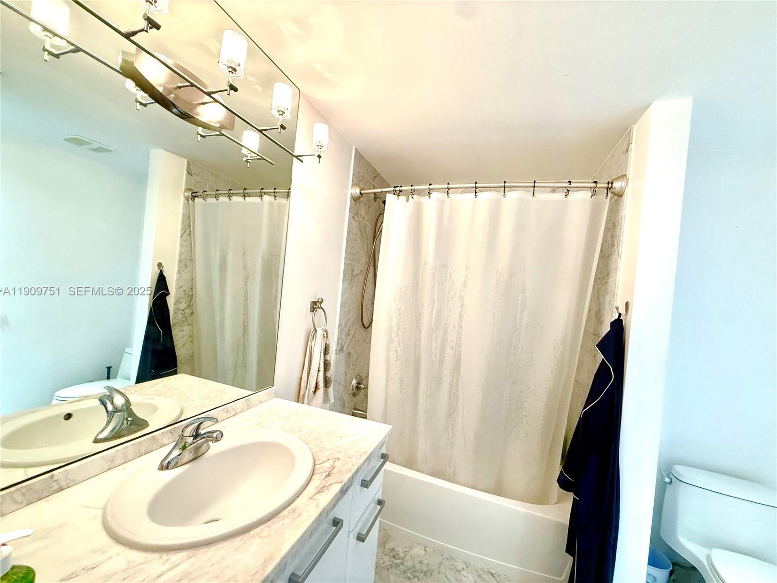 A bathroom features a vanity with a marble countertop, a mirror, and a shower-tub combination — 253 NE 2nd St # 219, Miami FL 33132, MIAMI, FL