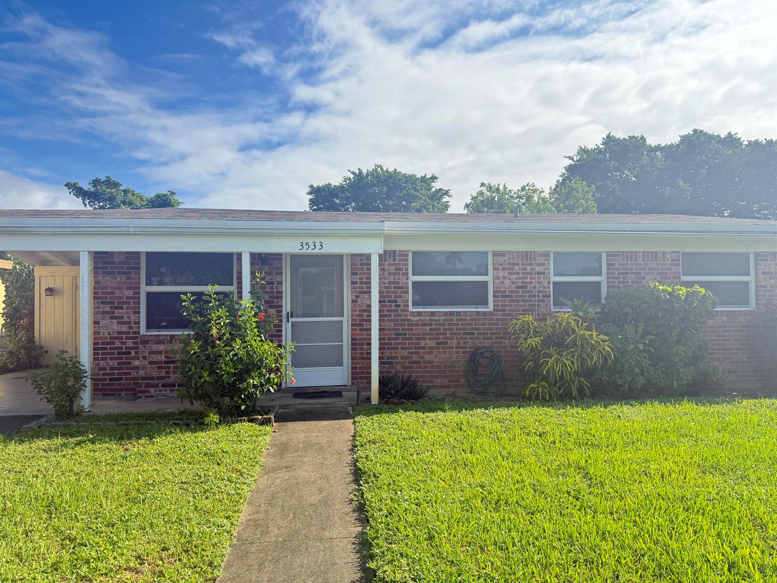 A single-story brick house features a front walkway, a covered entryway, and a green lawn — 3533 Florida Boulevard, Palm Beach Gardens FL 33410, PALM BEACH GARDENS, FL