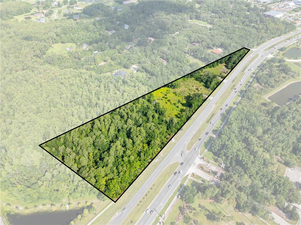 An aerial view shows a triangular plot of land bordered by a multi-lane highway — PLEASANT HILL RD ROAD, KISSIMMEE, FL