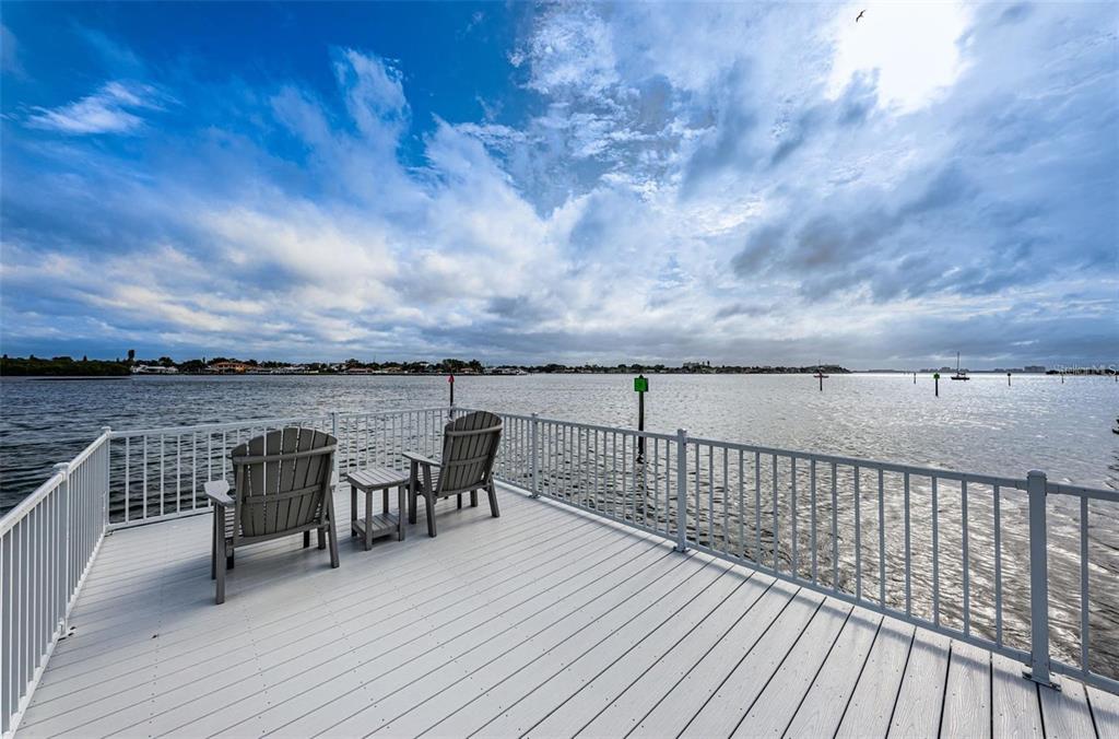 A white deck with two chairs overlooks a large body of water under a cloudy sky — 1859 SHORE DRIVE S UNIT 107, SOUTH PASADENA, FL