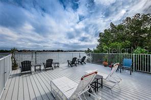 A spacious outdoor deck features multiple chairs and lounge chairs overlooking a body of water — 1859 SHORE DRIVE S UNIT 107, SOUTH PASADENA, FL