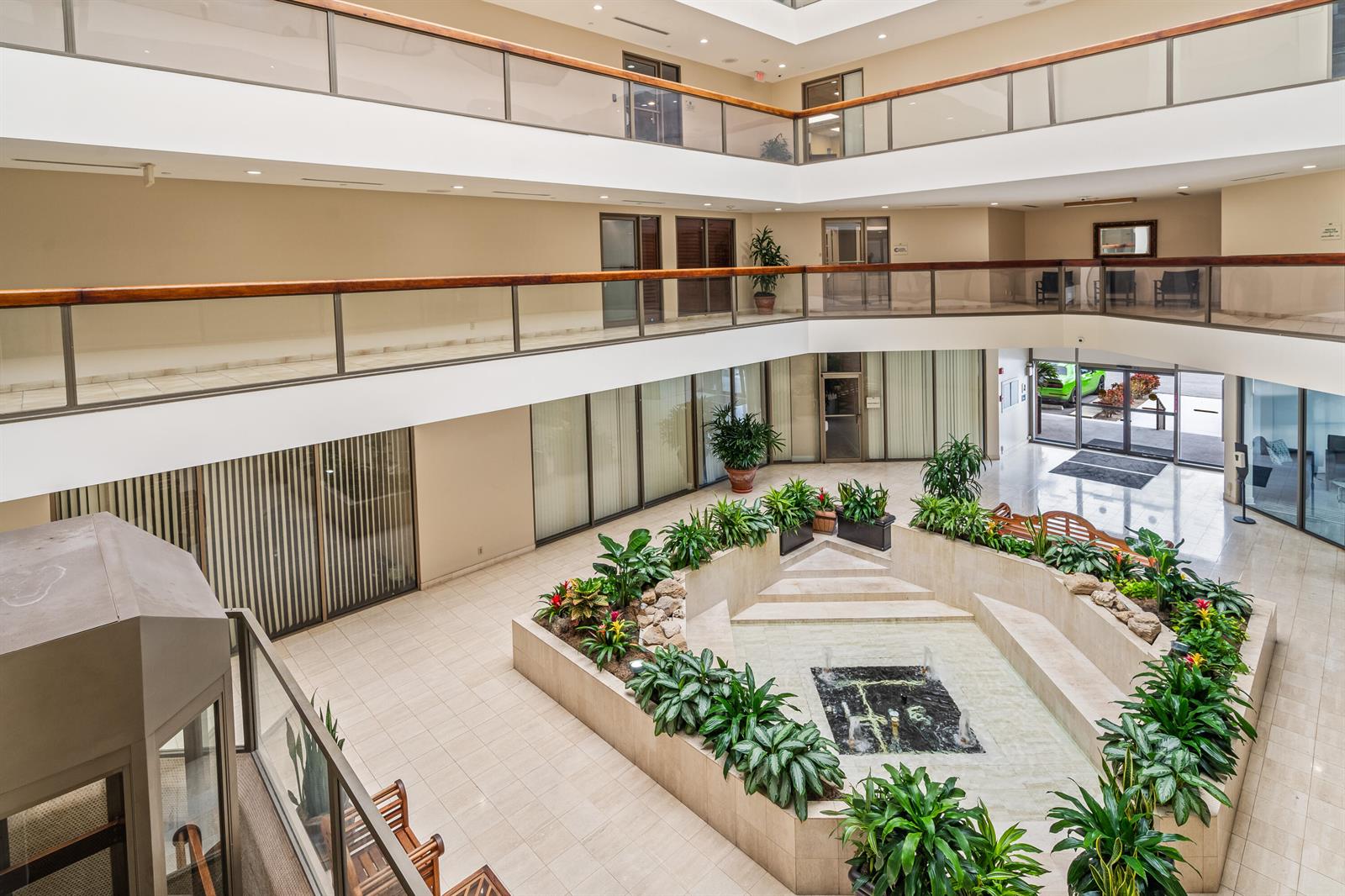 An indoor atrium features a tiered fountain, lush greenery, and multiple levels with glass railings — 631 Us-1, North Palm Beach FL 33408, NORTH PALM BEACH, FL