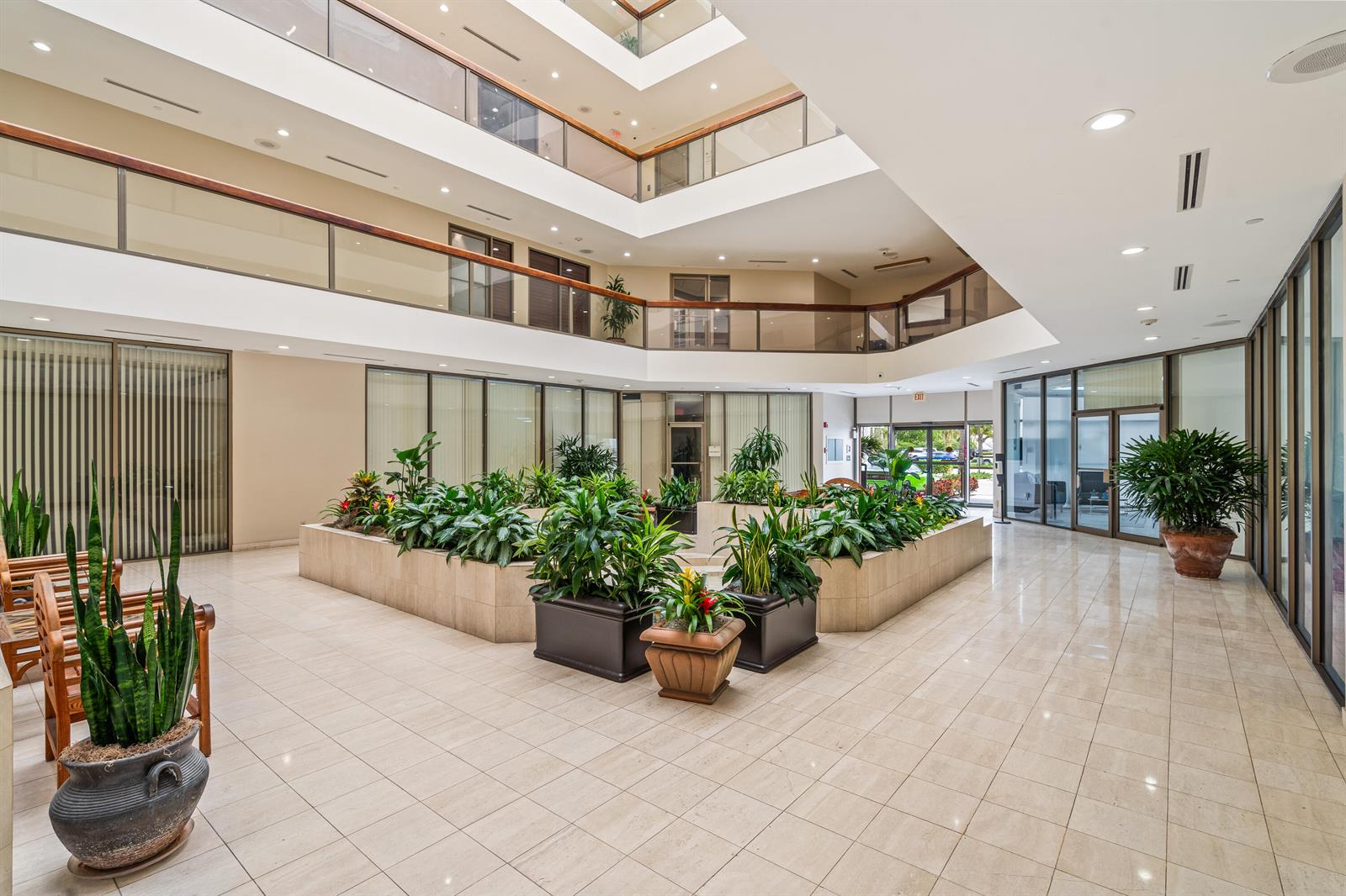 An indoor atrium features a multi-level balcony, tiled floors, and a central planter with greenery — 631 Us-1, North Palm Beach FL 33408, NORTH PALM BEACH, FL