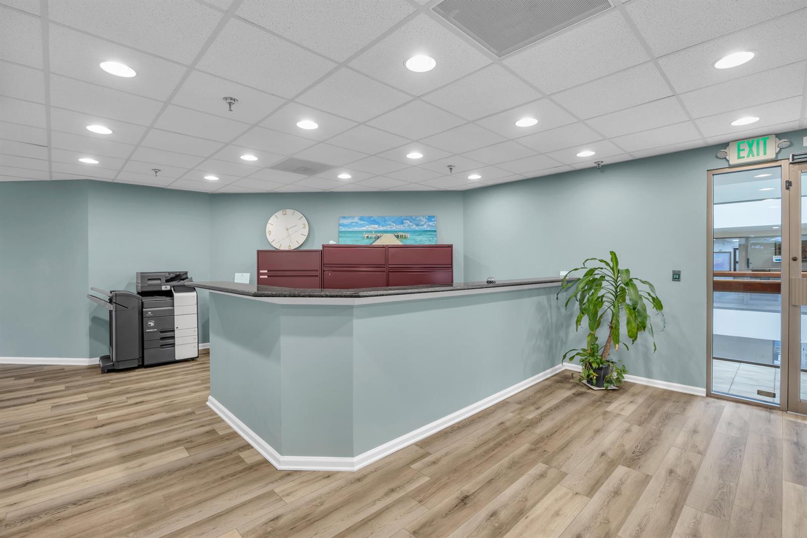 A reception area features a light blue desk, wood-look flooring, a printer, and an exit door — 631 Us-1, North Palm Beach FL 33408, NORTH PALM BEACH, FL