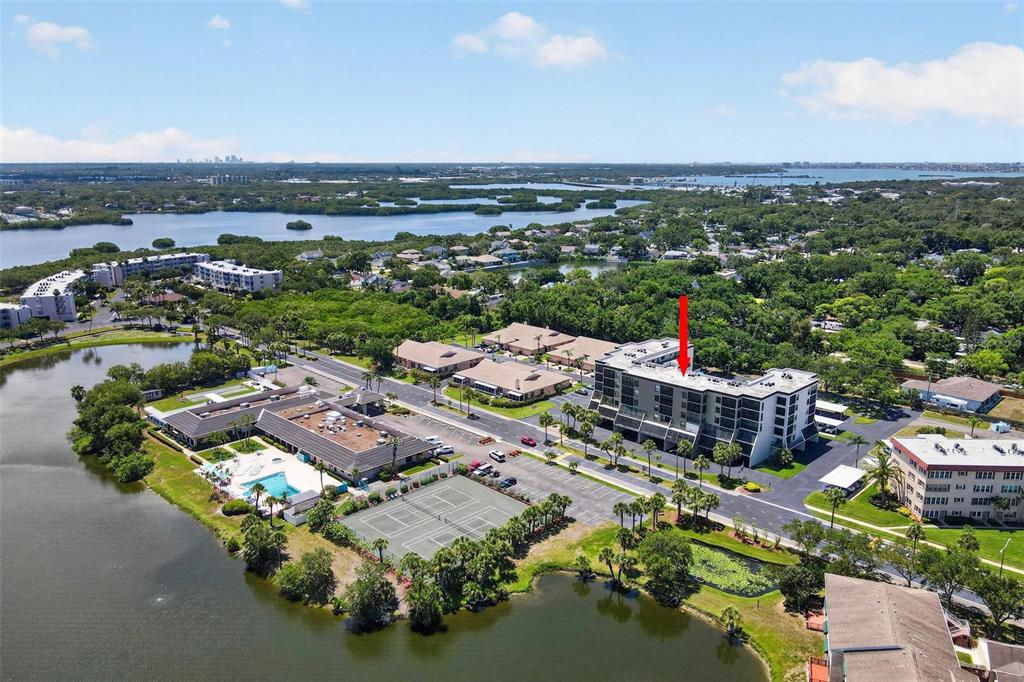 An aerial view shows a multi-story apartment building with a red arrow pointing to it — 9860 62ND TERRACE N UNIT 1043, ST PETERSBURG, FL