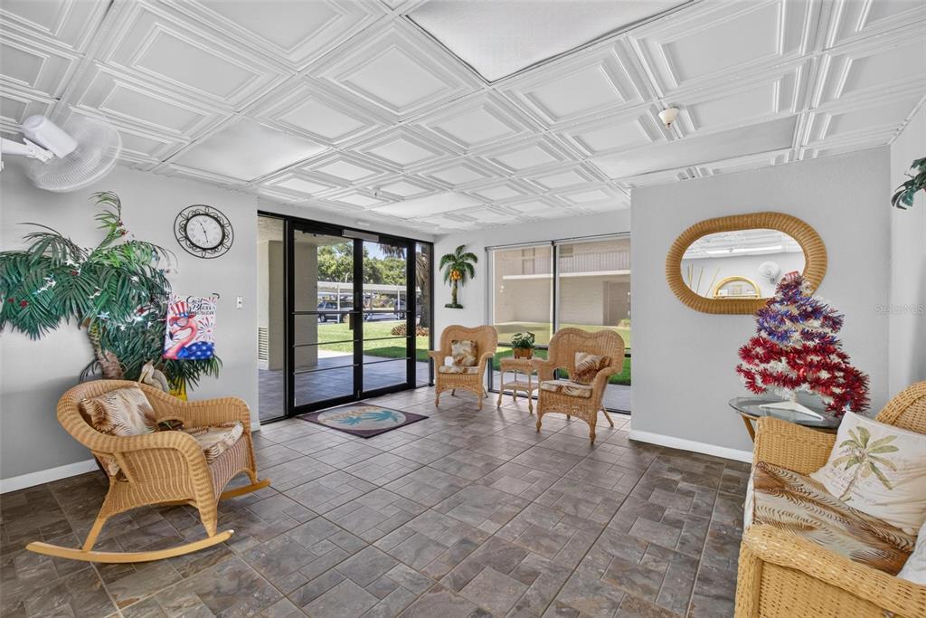 A lobby with tiled floors, wicker furniture, a drop ceiling, and glass doors to outside — 9860 62ND TERRACE N UNIT 1043, ST PETERSBURG, FL