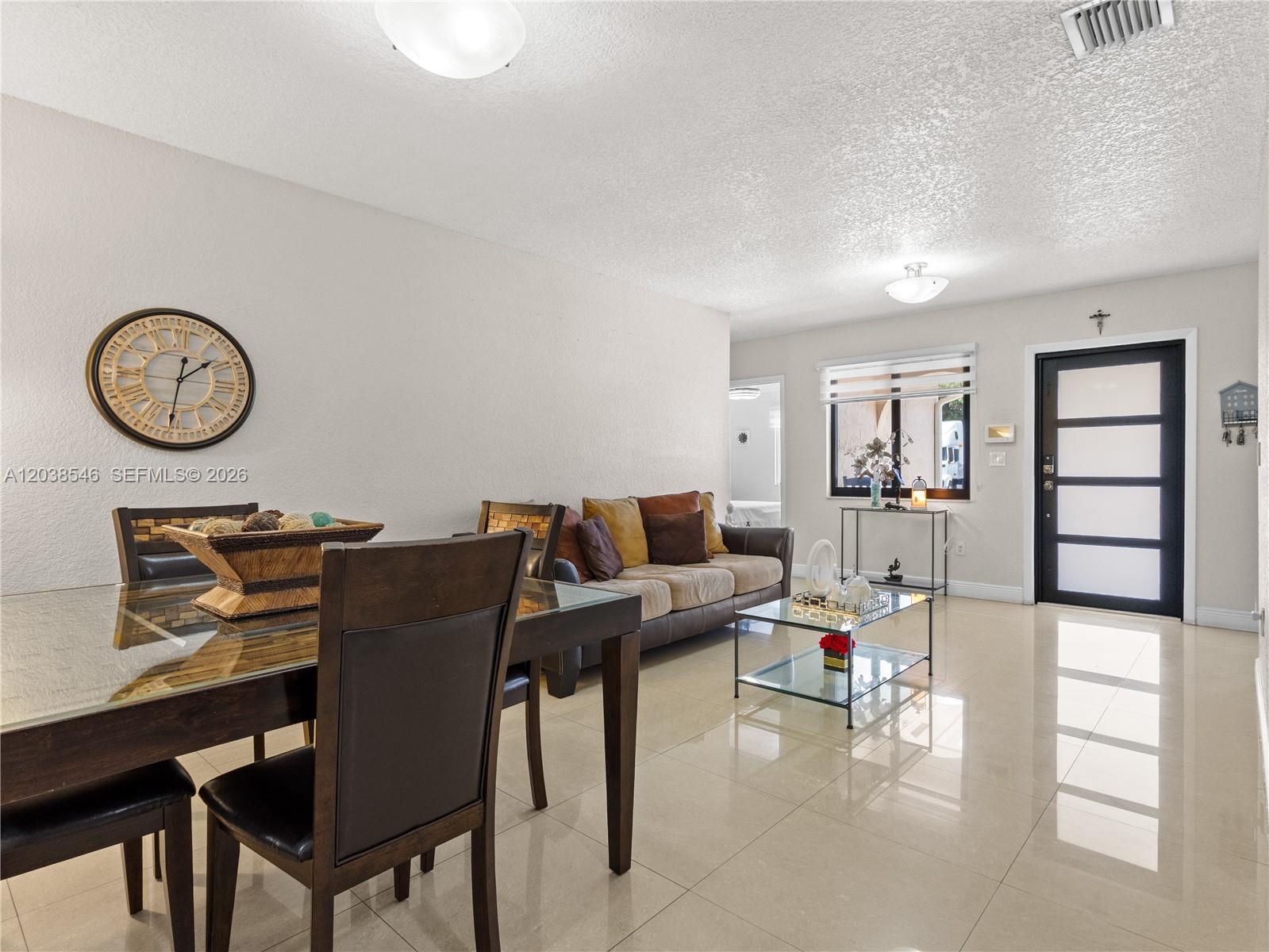 A living and dining area features tile floors, a glass table, and a dark front door — 10532 NW 30th Ave., Miami FL 33147, MIAMI, FL