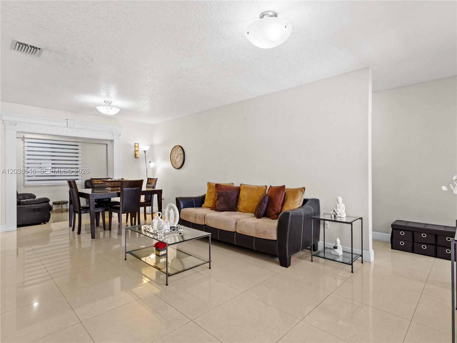 A living and dining area features tile flooring, a dark sofa, and a glass coffee table — 10532 NW 30th Ave., Miami FL 33147, MIAMI, FL