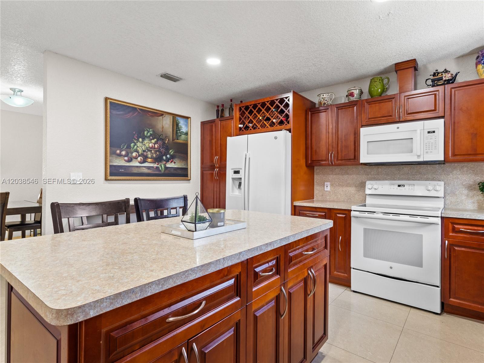 A kitchen features dark wood cabinets, white appliances, and a central island with a countertop — 10532 NW 30th Ave., Miami FL 33147, MIAMI, FL