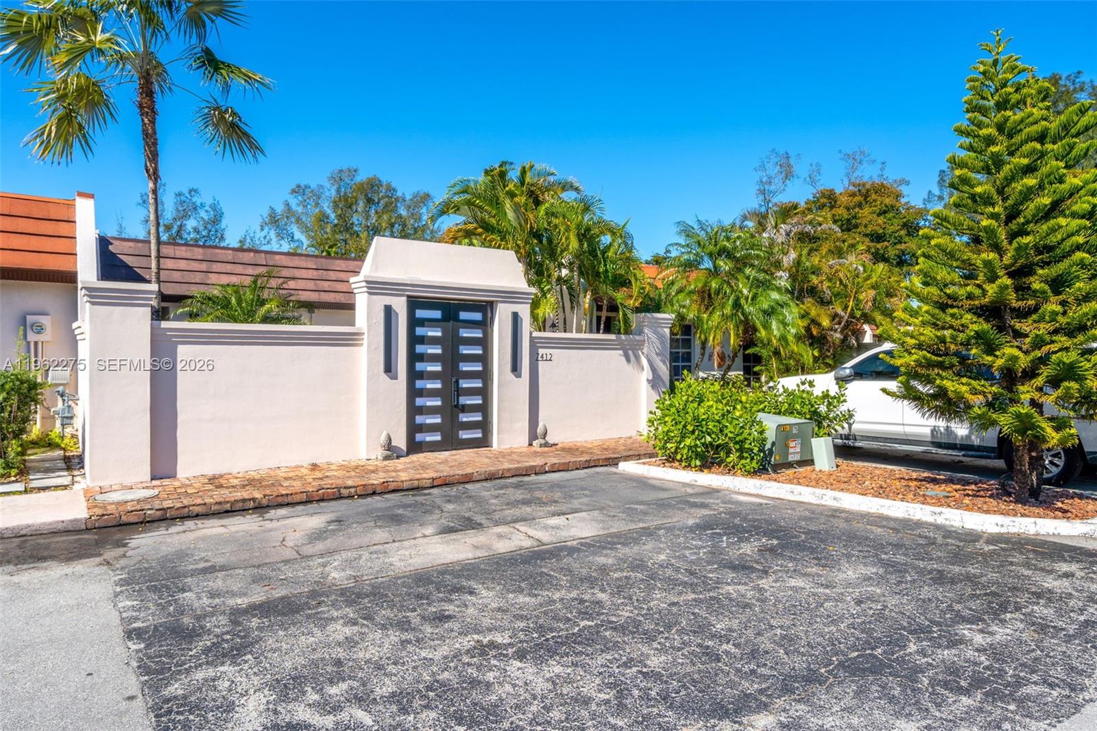 A gated entrance with a dark double door is set into a light-colored stucco wall — 7412 Big Cypress Dr, Miami Lakes FL 33014, MIAMI LAKES, FL