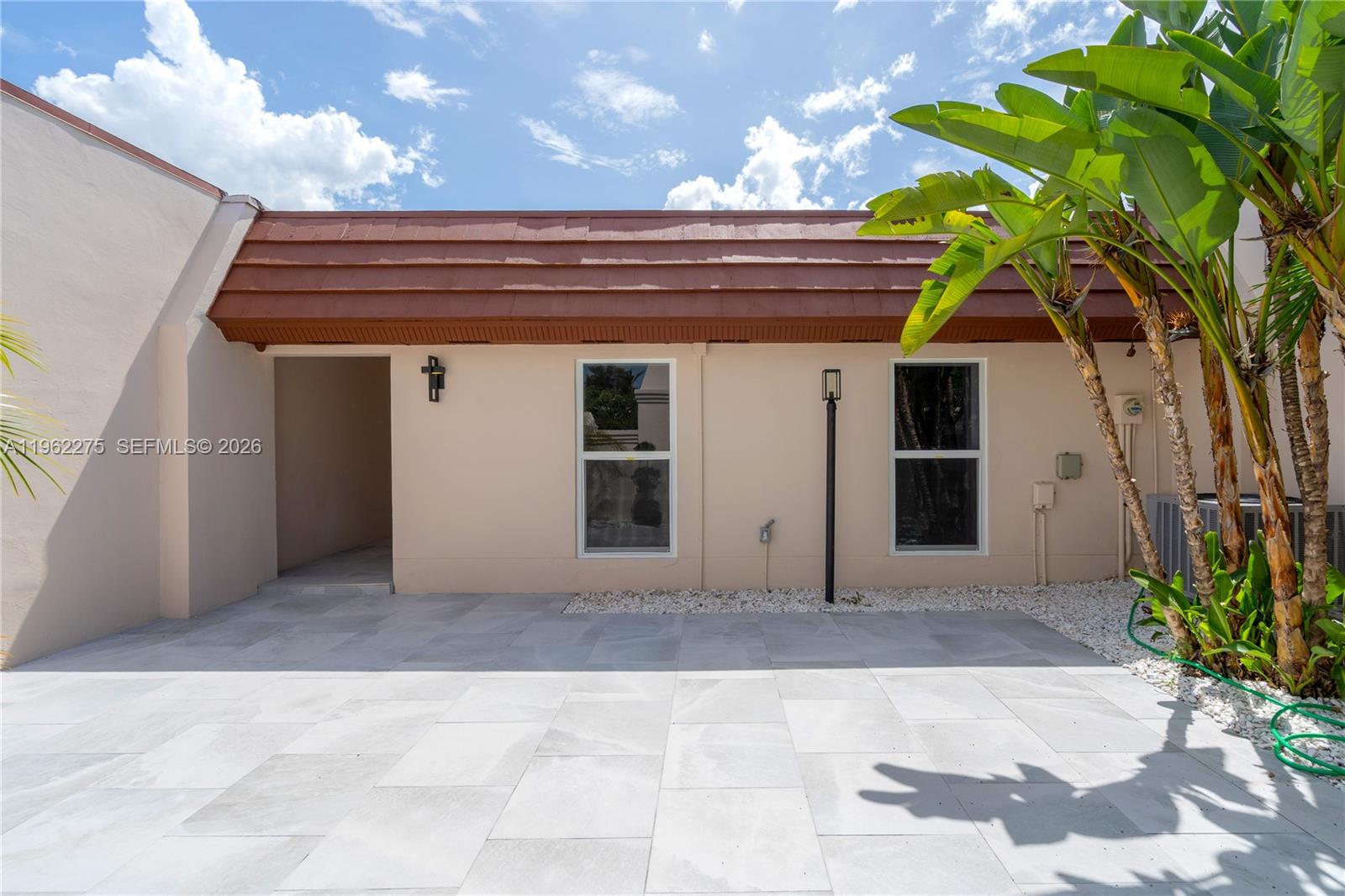 A beige exterior wall features two windows, a recessed entryway, and a brown tiled roof — 7412 Big Cypress Dr, Miami Lakes FL 33014, MIAMI LAKES, FL