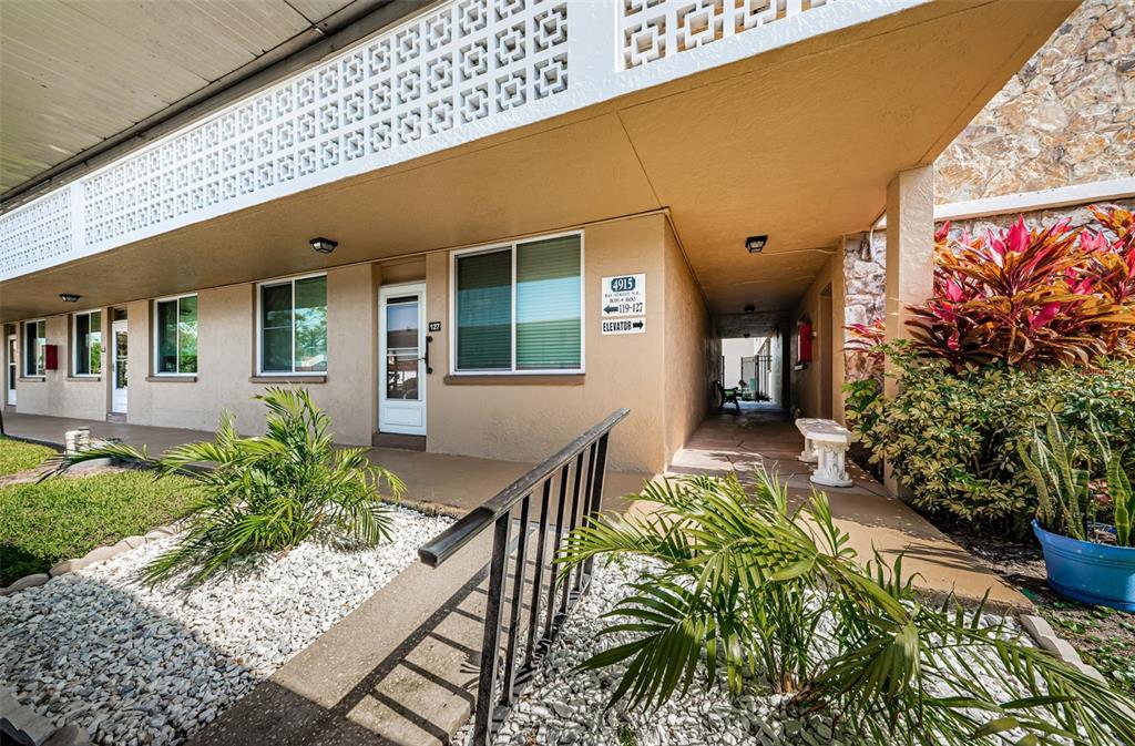 An exterior view of a building walkway with a ramp, landscaping, and unit signage — 4915 BAY STREET NE UNIT 126, ST PETERSBURG, FL