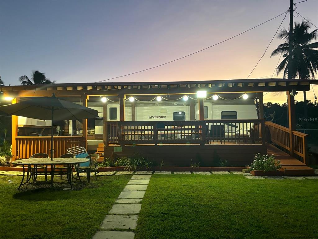 A travel trailer sits on a wooden deck under a pergola at dusk — Las Picuas Beach BO. ZORZAL ORCHARD UNIT 6, RIO GRANDE, PR