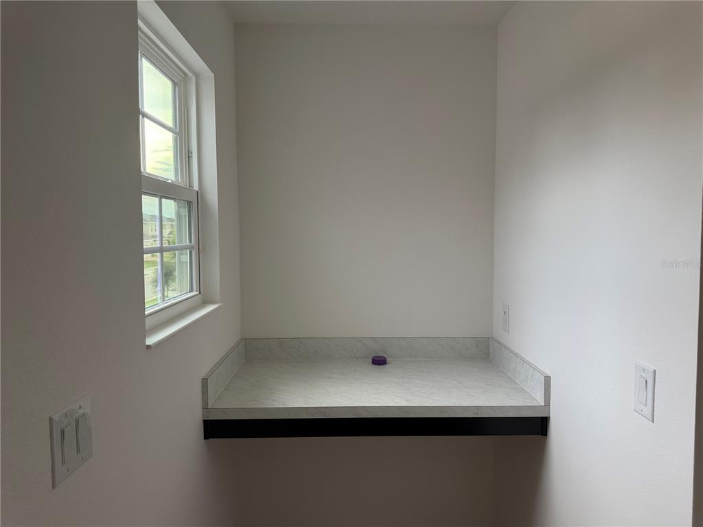 A laundry room features a white countertop, a window, and electrical outlets on the walls — 911 AVENAL LANE, DAVENPORT, FL