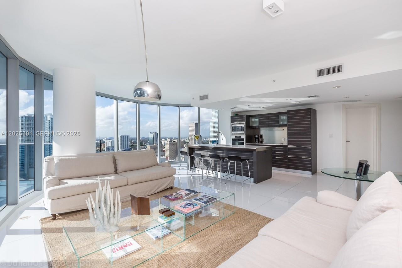 A modern open-concept living room and kitchen feature floor-to-ceiling windows with city views — 200 Biscayne Boulevard Way # 3102, Miami FL 33131, MIAMI, FL