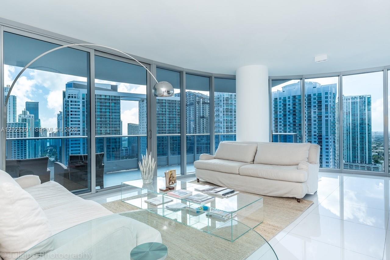 A modern living room features white sofas, a glass coffee table, and floor-to-ceiling windows — 200 Biscayne Boulevard Way # 3102, Miami FL 33131, MIAMI, FL