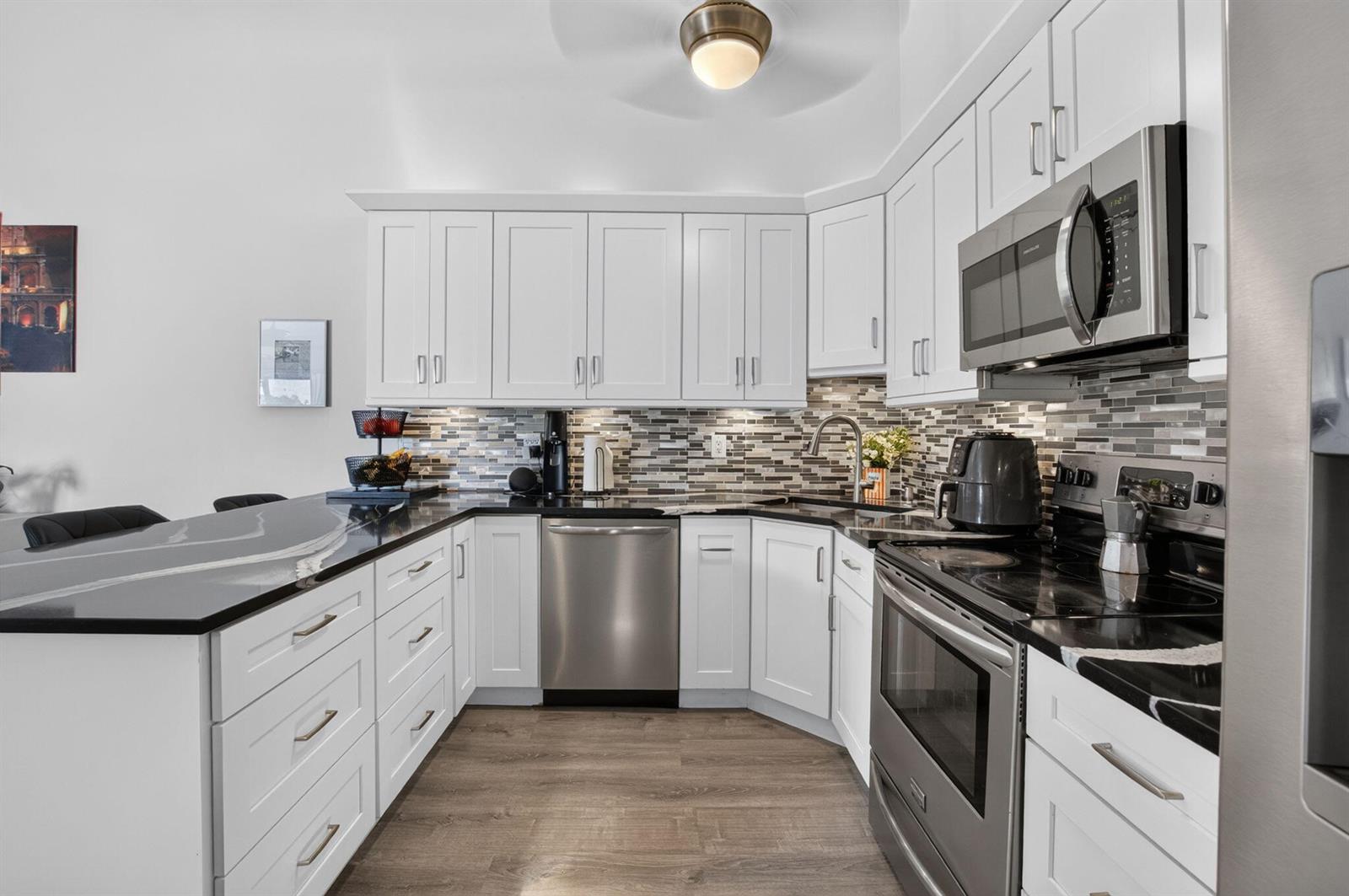 A kitchen island with black countertops overlooks a living room with a vaulted ceiling — 9622 Boca Gardens Parkway # B, Boca Raton FL 33496, BOCA RATON, FL