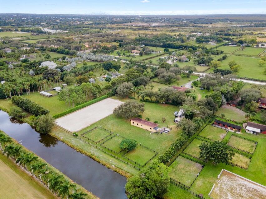 An aerial view shows a rural property with horse paddocks, a riding arena, and stables — 16693 Deer Path Lane, Wellington FL 33470, WELLINGTON, FL