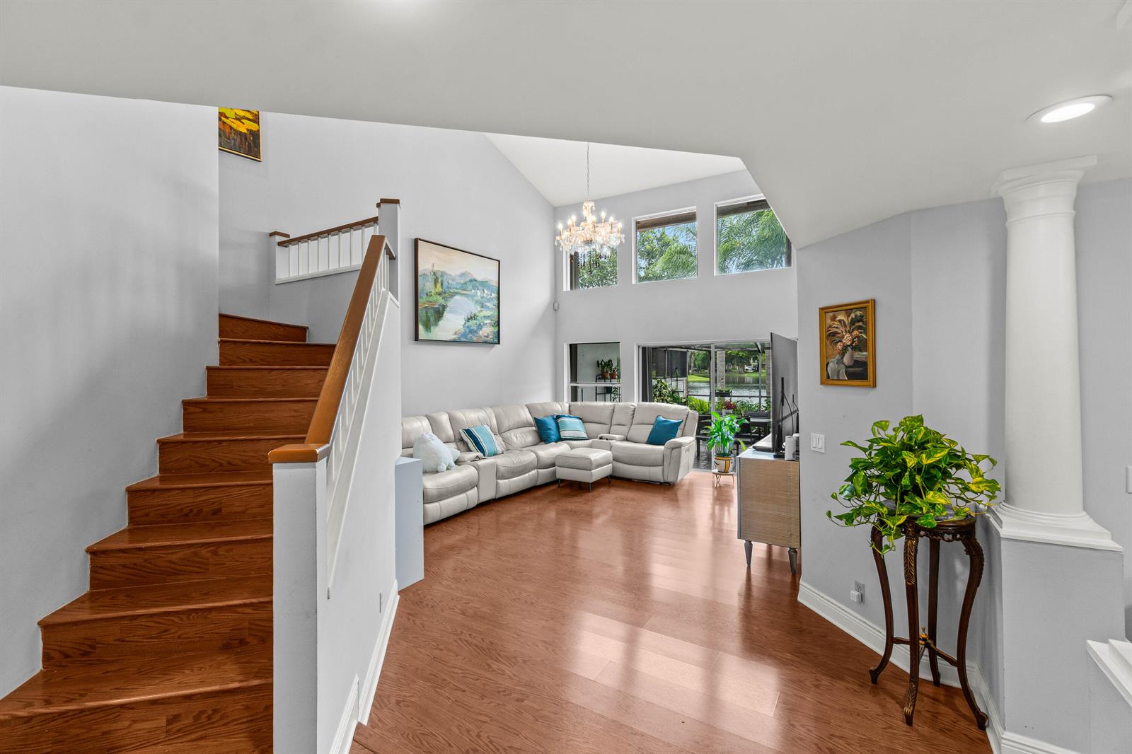 A living room with hardwood floors, a white sectional sofa, and a staircase — 2011 NW 53rd Street, Boca Raton FL 33496, BOCA RATON, FL