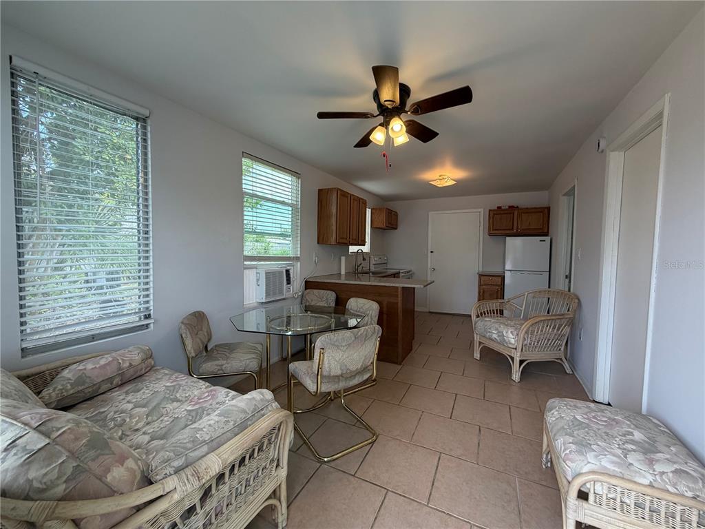A dining area with tile floors, a glass table, and a kitchen in the background — 8513 HERBISON AVENUE, NORTH PORT, FL