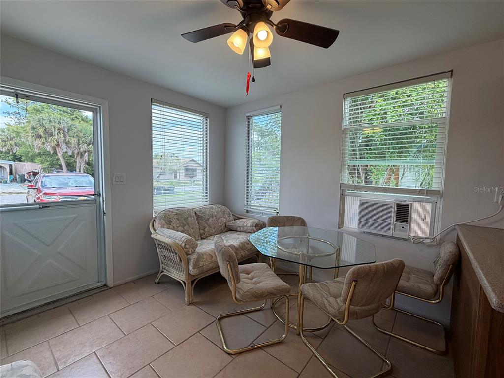 A sunroom features tile flooring, a glass dining table, wicker seating, and a window air conditioner — 8513 HERBISON AVENUE, NORTH PORT, FL