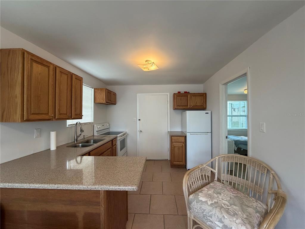 A kitchen features oak cabinets, granite countertops, tile flooring, and a white refrigerator — 8513 HERBISON AVENUE, NORTH PORT, FL