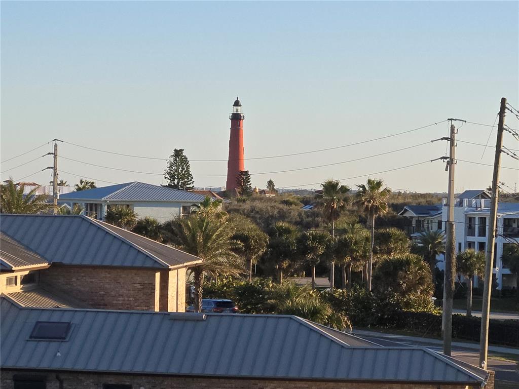 An elevated view shows a red lighthouse rising above trees, houses, and utility poles — 4799 S ATLANTIC AVENUE UNIT 4080, PORT ORANGE, FL